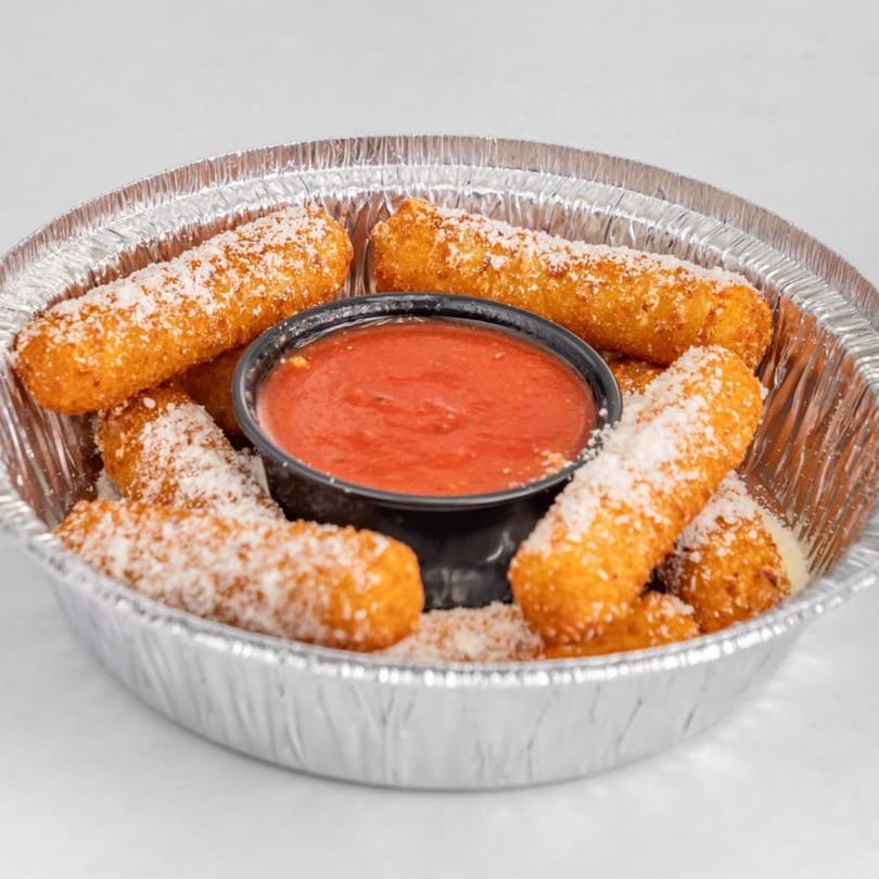 Golden-brown mozzarella sticks, sprinkled with Parmesan cheese, in a foil container with a side of marinara sauce.