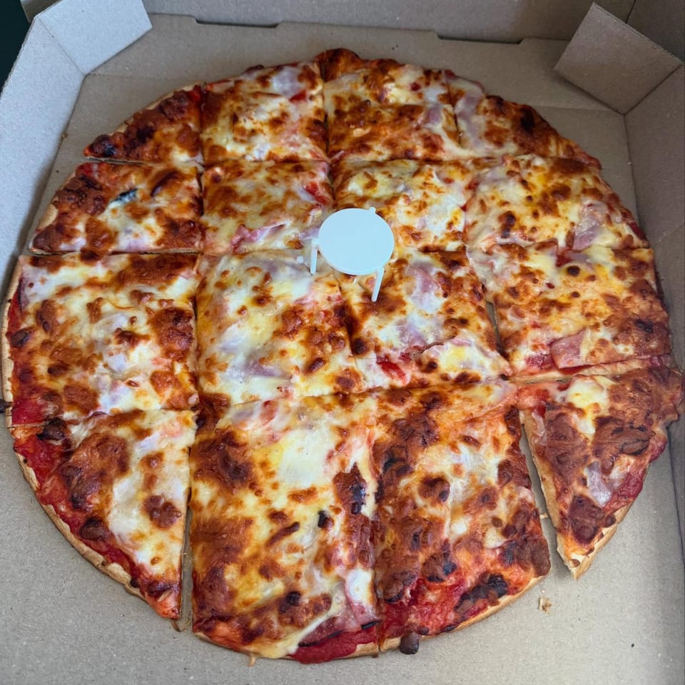 Hampton Hill Pizza's square-cut cheese pizza with a light blue pizza saver in a cardboard box.