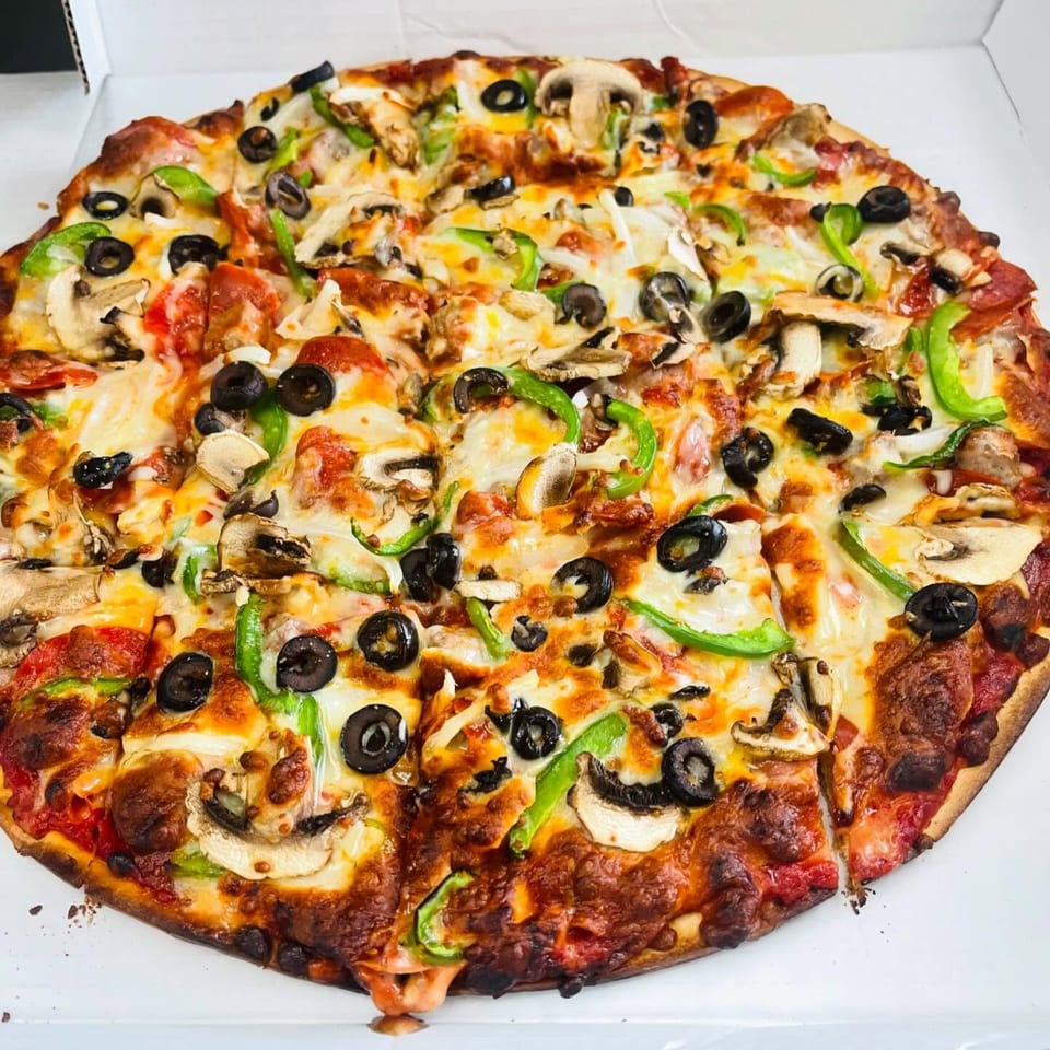 Hampton Hill Pizza's whole pizza with mushrooms, green peppers, black olives, and pepperoni in a white box.