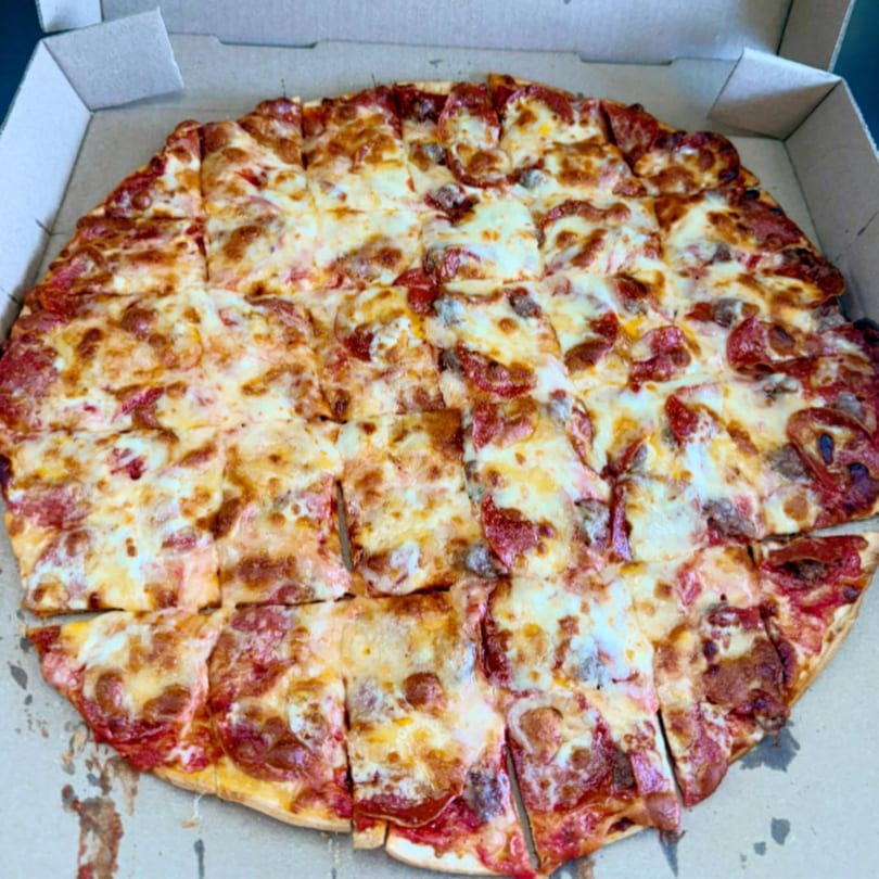 Hampton Hill Pizza's pepperoni and sausage pizza, cut into squares, in a cardboard box.