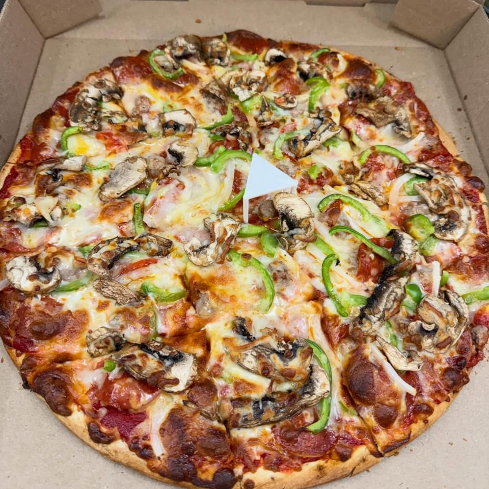 Hampton Hill Pizza's supreme pizza with mushrooms, green peppers, onions, and pepperoni in a box.